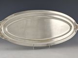 an oval silver tray with a fish design on it