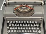 an old typewriter sitting on a table with a clock on it