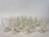 six verres à vin transparents sont alignés sur une surface blanche