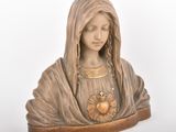 La statue de la Vierge Marie tient un cœur entre ses mains.