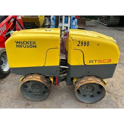 yellow and black machine sitting on top of a dirt field