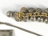 two pieces of silver and gold jewelry on a white surface