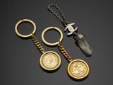 three gold key chains with a clock and a keychain on a black background