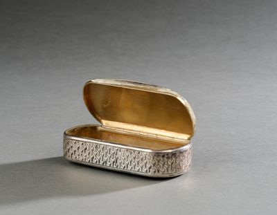 une boîte en argent avec un couvercle en or posée sur une table