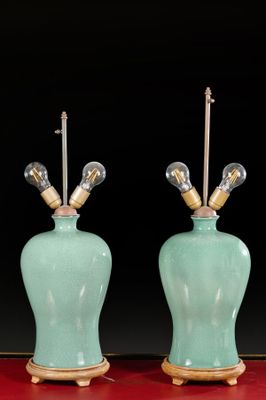 pair of green ceramic lamps on red table with black background