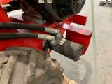 a close up of a red tractor with a hose attached to it