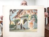un homme tenant un tableau représentant un chien devant une maison
