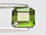 un gros plan sur une tourmaline verte taillée à l'aide d'une pince