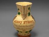 un vase jaune orné d'une inscription, posé sur une table
