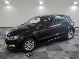 La Volkswagen Polo noire est garée dans une pièce au sol carrelé.