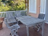 a wooden table and chairs on a patio next to a potted plant