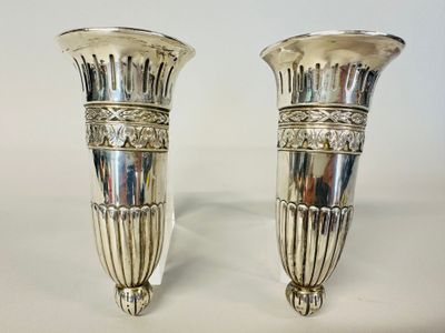 une paire de vases en argent posés sur une table blanche, sur fond blanc