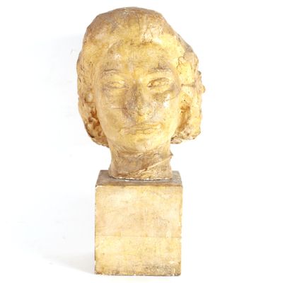 statue représentant la tête d'une femme, posée sur un socle en bois, sur fond blanc
