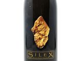 a close up of a bottle of wine with a piece of gold on it