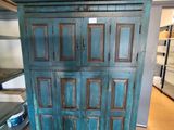 une armoire bleue au milieu d'une pièce, à côté d'un lit