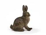 small bronze rabbit figurine sitting on a white surface