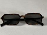 des lunettes de soleil posées sur une surface blanche, avec un fond blanc
