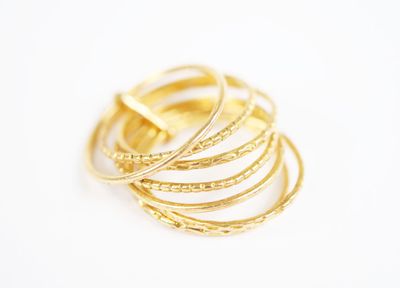 a close up of a stack of gold rings on a white surface