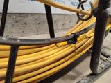 a yellow hose on the ground next to a black pipe