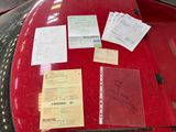 a lot of papers on the hood of a red car