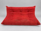 un canapé-futon rouge sur lequel est posé un coussin rouge