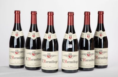six bouteilles de vin rouge alignées sur une surface blanche