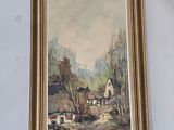 painting of a farm scene in a gold frame on a glass table