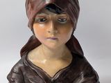 statue of a woman wearing a brown hat and a brown jacket