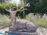 une statue représentant un cerf assis dans l'herbe