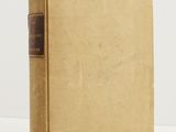 a brown book sitting on top of a table next to a white wall