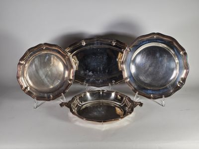 trois plats en métal argenté et une assiette en argent posés sur un fond blanc