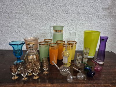 de nombreux verres et vases de différentes couleurs posés sur une table