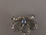 un gros plan d'une broche en argent sertie d'une pierre bleue