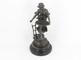 bronze statue of a woman sitting on a chair with a cane