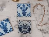 four blue and white tile coasters on a marble table