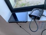 une tablette posée sur le rebord d'une fenêtre, à côté d'un téléphone