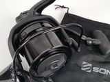 a close up of a fishing reel and a bag on a table