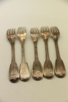 six cuillères en argent et une fourchette posées sur un plateau blanc