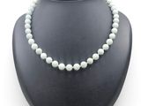 a close up of a necklace on a mannequin with a white background