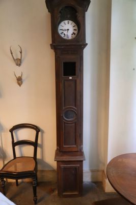 une horloge de parquet dans un coin de la pièce, à côté d'un fauteuil