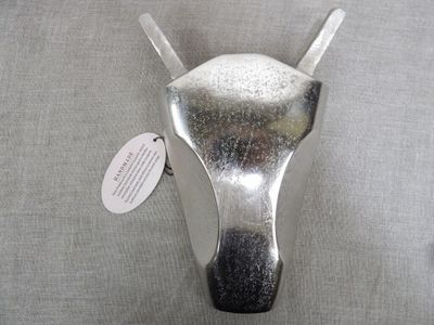 a silver cow head mounted on the wall with a tag
