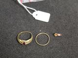 two gold rings and a pink stone ring on a black surface