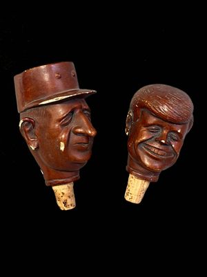 une paire de têtes en bois représentant un homme et une femme coiffés de chapeaux