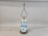 a blue and white vase on a table with a lamp on it