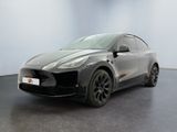 un SUV Tesla gris garé dans une pièce au sol noir