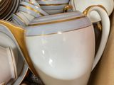 a box full of white and gold china dishes and cups