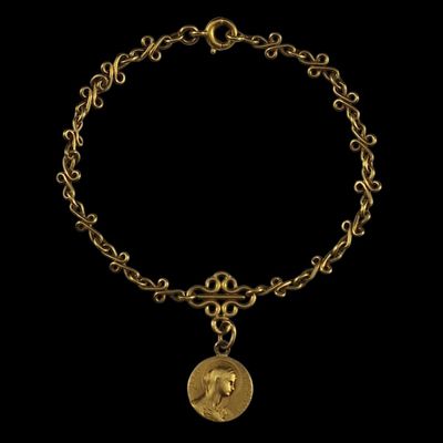 Gros plan sur un bracelet en or orné d'une pièce de monnaie