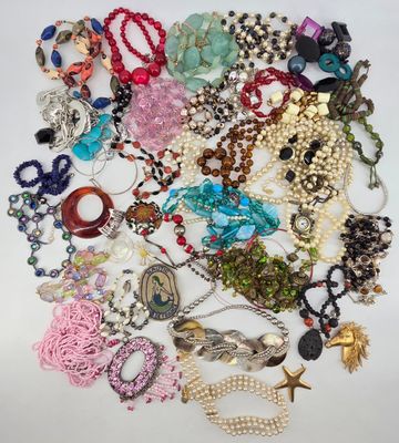 a pile of assorted necklaces and bracelets on a white surface