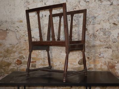 two wooden chairs sitting on a table in front of a brick wall