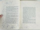 a person holding an open book with a drawing on it